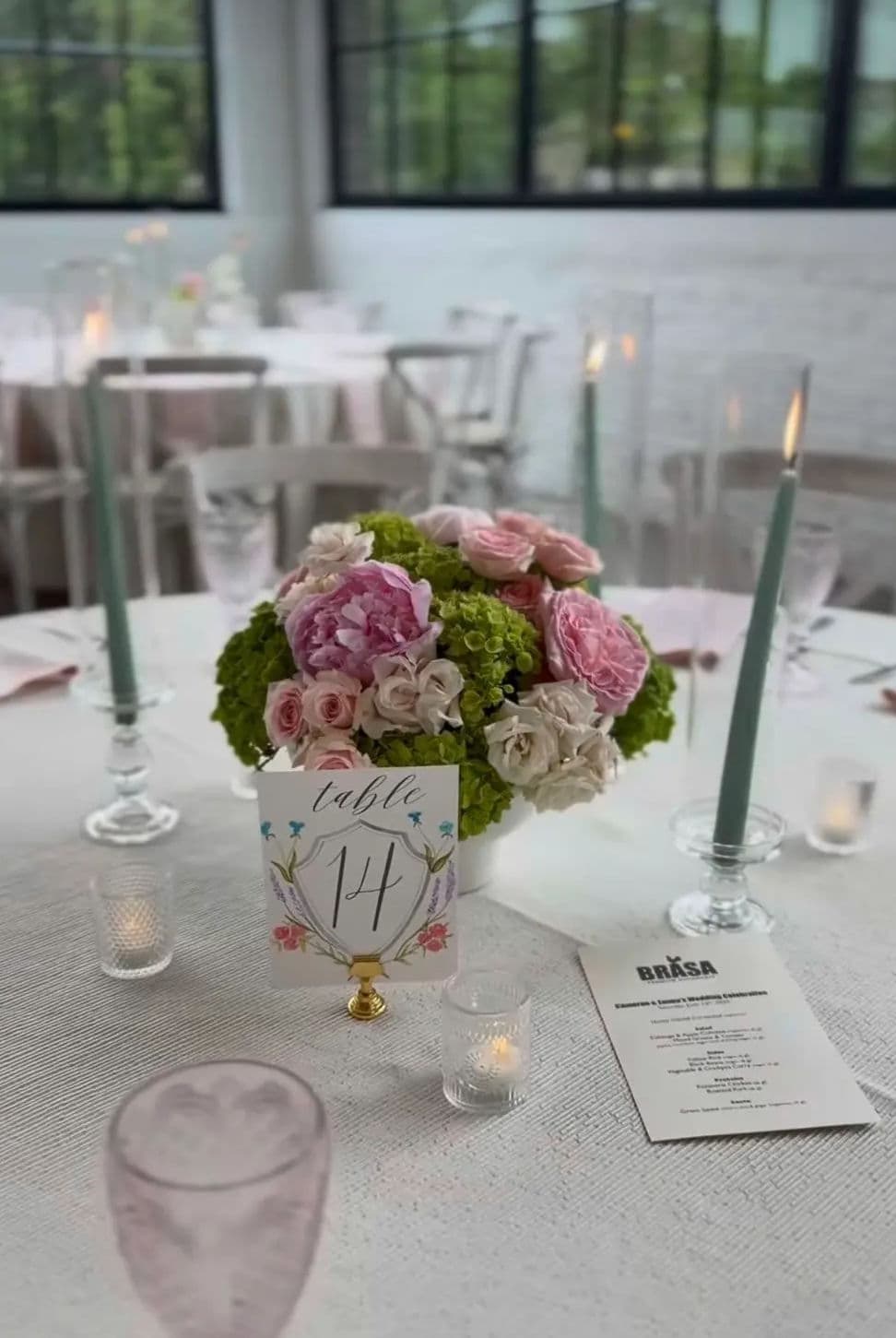 Elegant wedding table setting with floral centerpiece, candles, and table number 14.