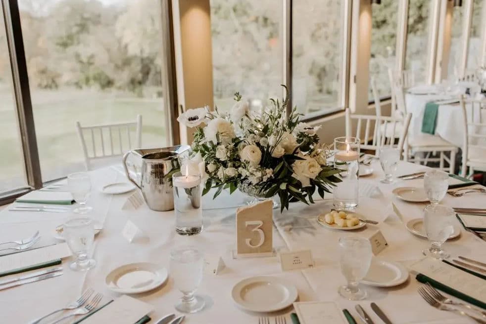 Elegant wedding reception table with floral centerpiece, candlelight, and place settings.