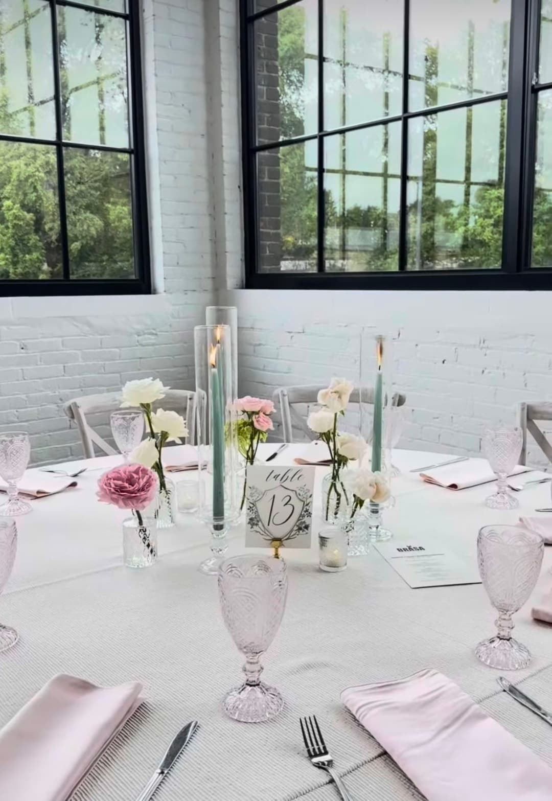 Elegant table setting with pink flowers and candles in a bright, modern venue.