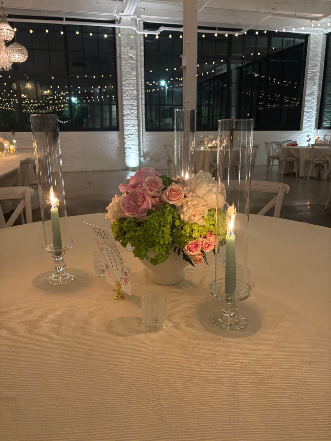 Elegant floral centerpiece with roses and greenery, candles on a beautifully set table.