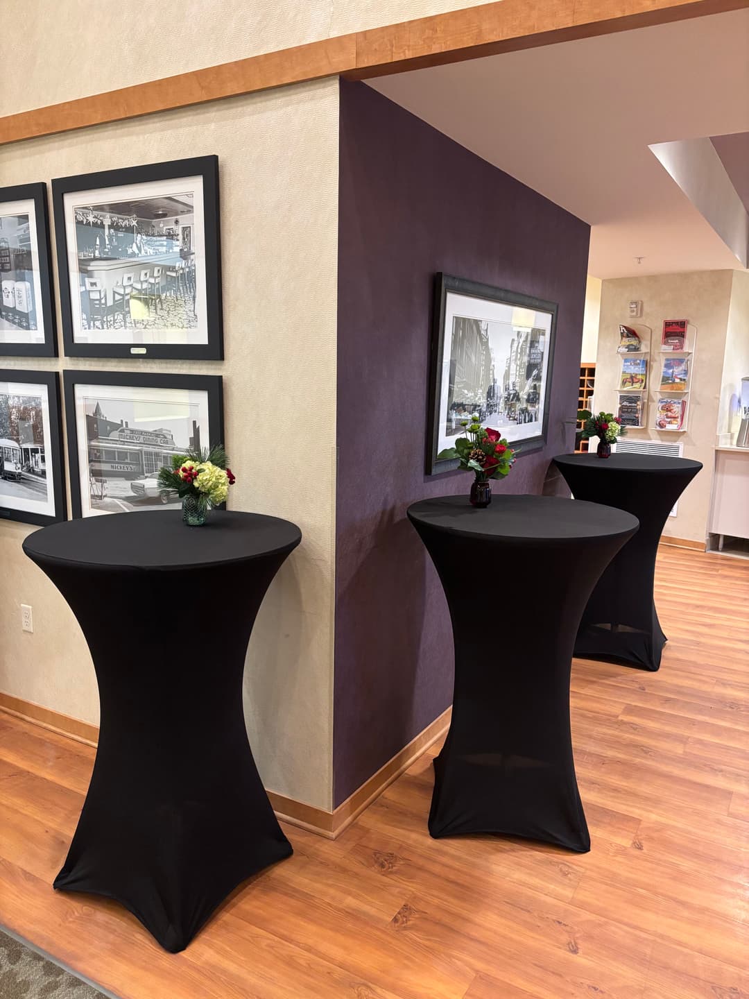 Three tall black tables with floral arrangements in a modern event space.