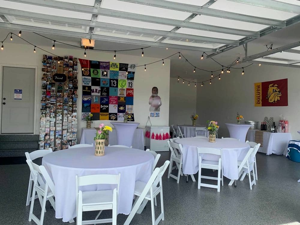 Decorated garage venue with round tables, string lights, and a colorful photo display.