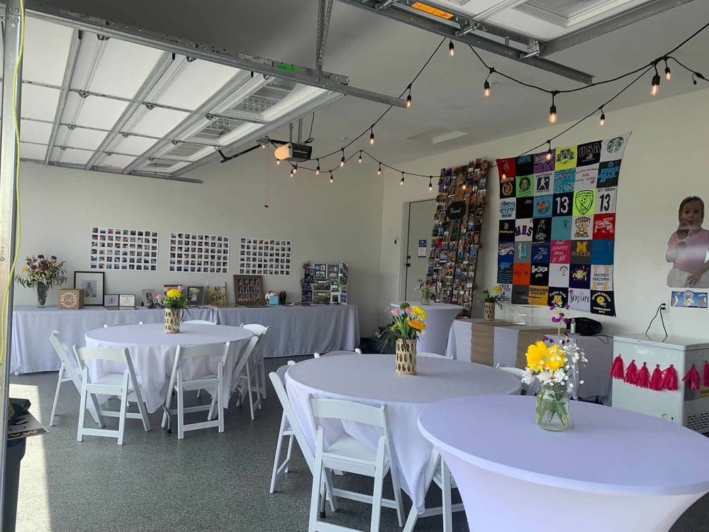 Event space featuring decorated tables, string lights, and a photo wall in a garage setting.