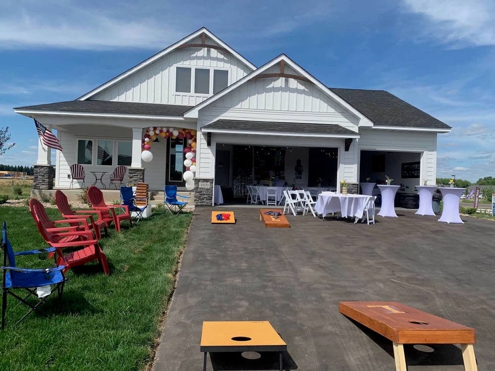 Modern white house with outdoor seating and corn hole game setup for a festive gathering.